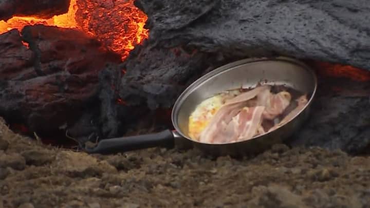 男人在活火山的熔岩上煮培根和鸡蛋